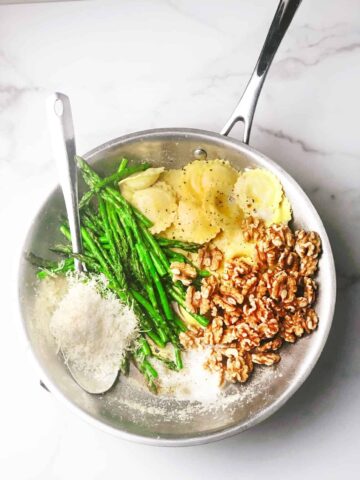 cheese ravioli with asparagus in a large silver pan