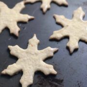 Snowflake Cookies on a dark gray sheet pan