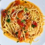 pasta with sauce and tomatoes on a white plate