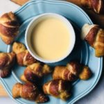 cooked pretzels on a blue plate with sauce in the middle
