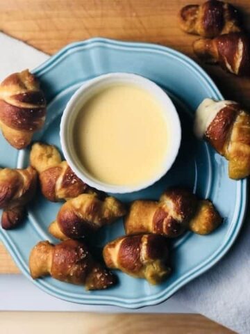 cooked pretzels on a blue plate with sauce in the middle