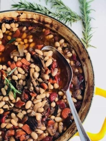 cassoulet in a large baking dish with a serving spoon in it