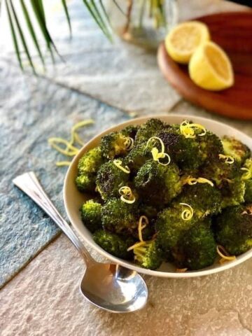 broccoli in a bowl on a stone surface with a spoon next to it