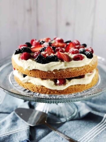 Italian berry cake on a cake stand on a blue table