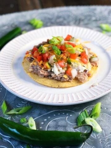 refried beans on a tostada with toppings on top.