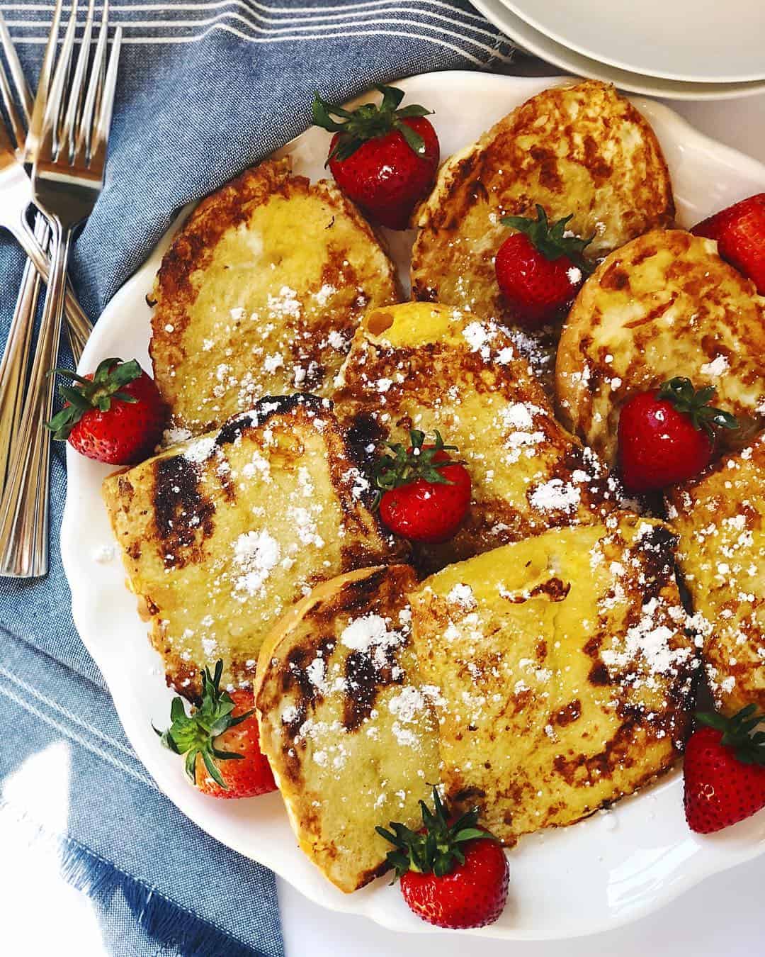 Brioche French toast with berries and powdered sugar on top.