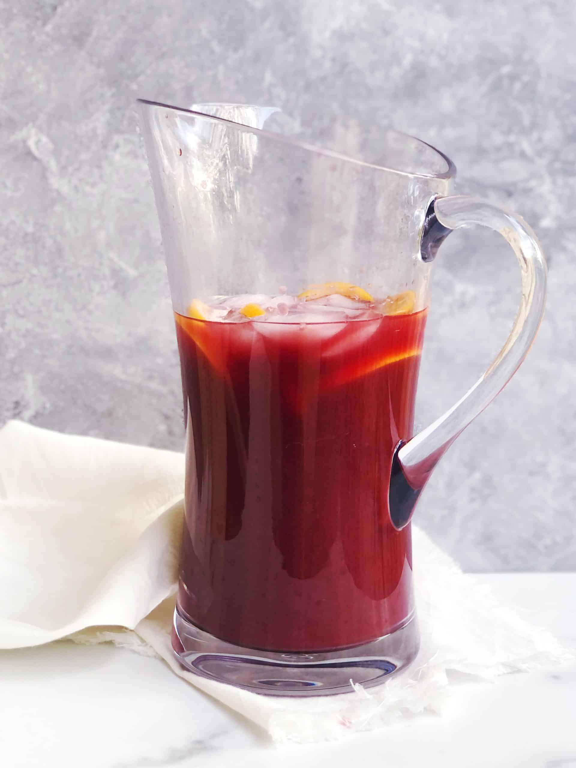 Aperol sangria in a large pitcher on a white counter.