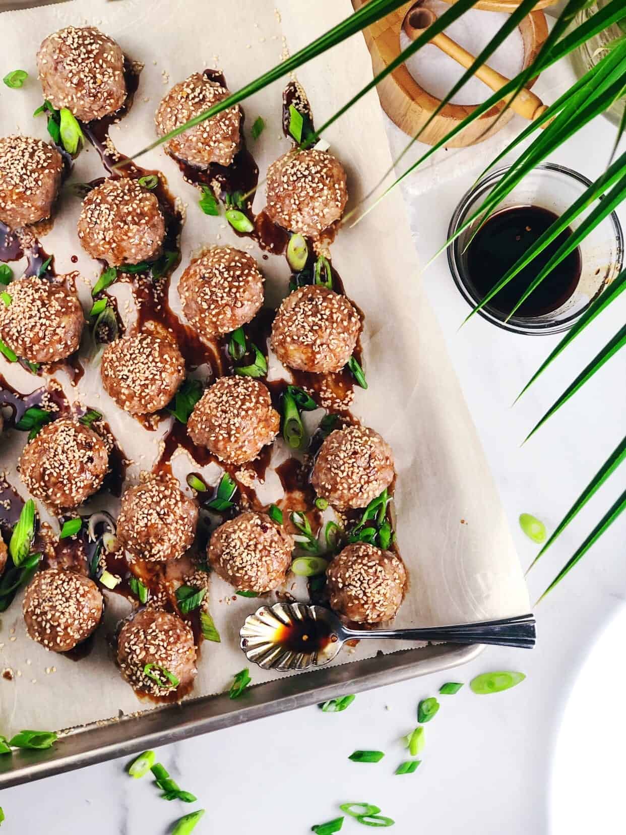 Asian oven baked meatballs on a plate with sauce drizzled over the top