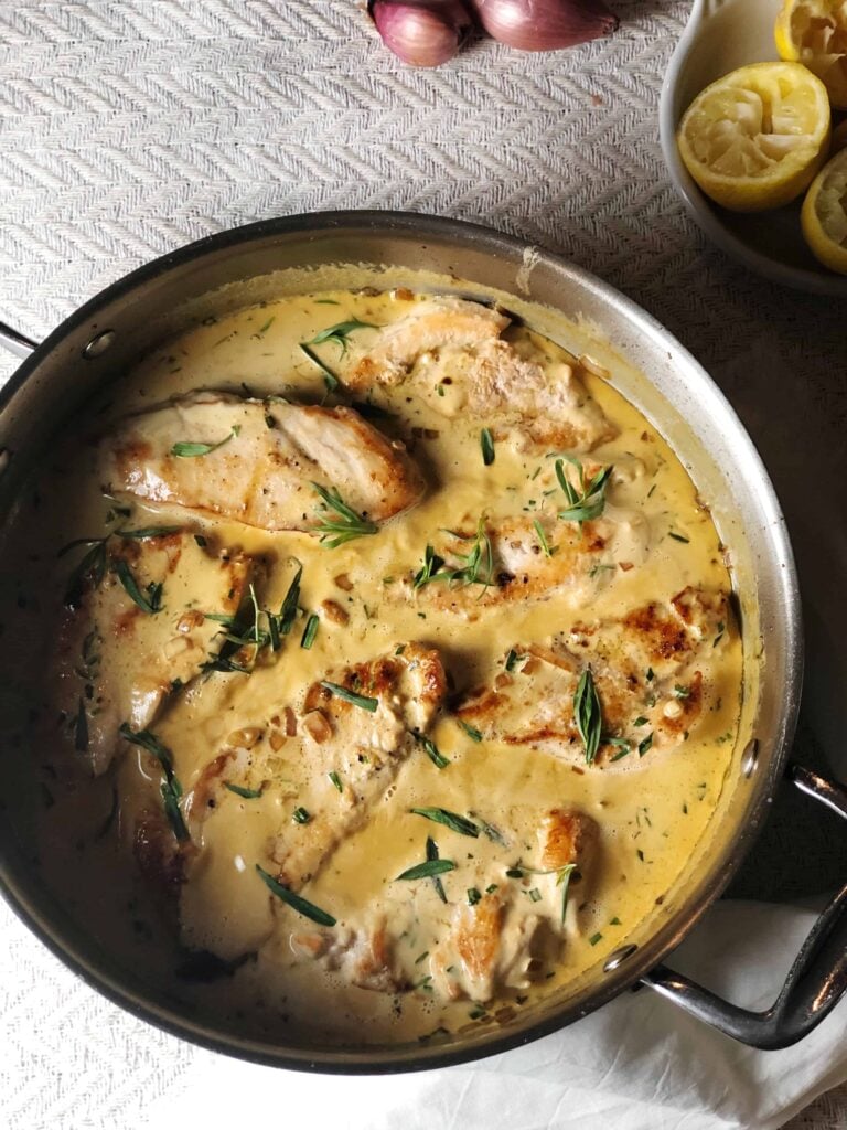 chicken with tarragon sauce in a pan on a white table