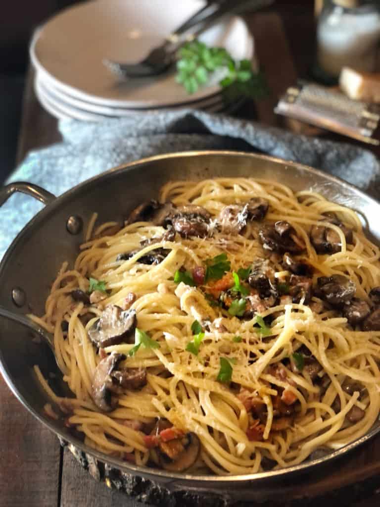 Pasta in saute pan on wood table.