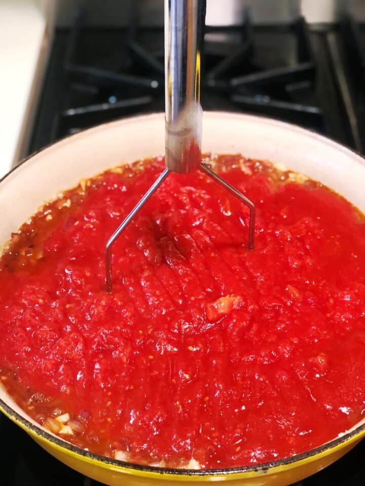 adding tomatoes to Italian gravy
