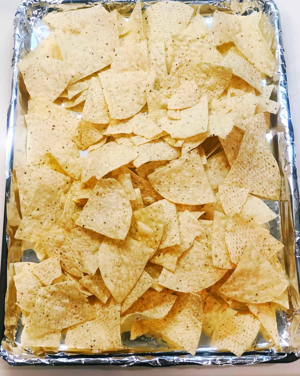 adding tortilla chips to sheet pan