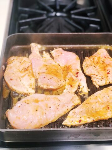 Southwest chicken breasts sizzling on a stove top.