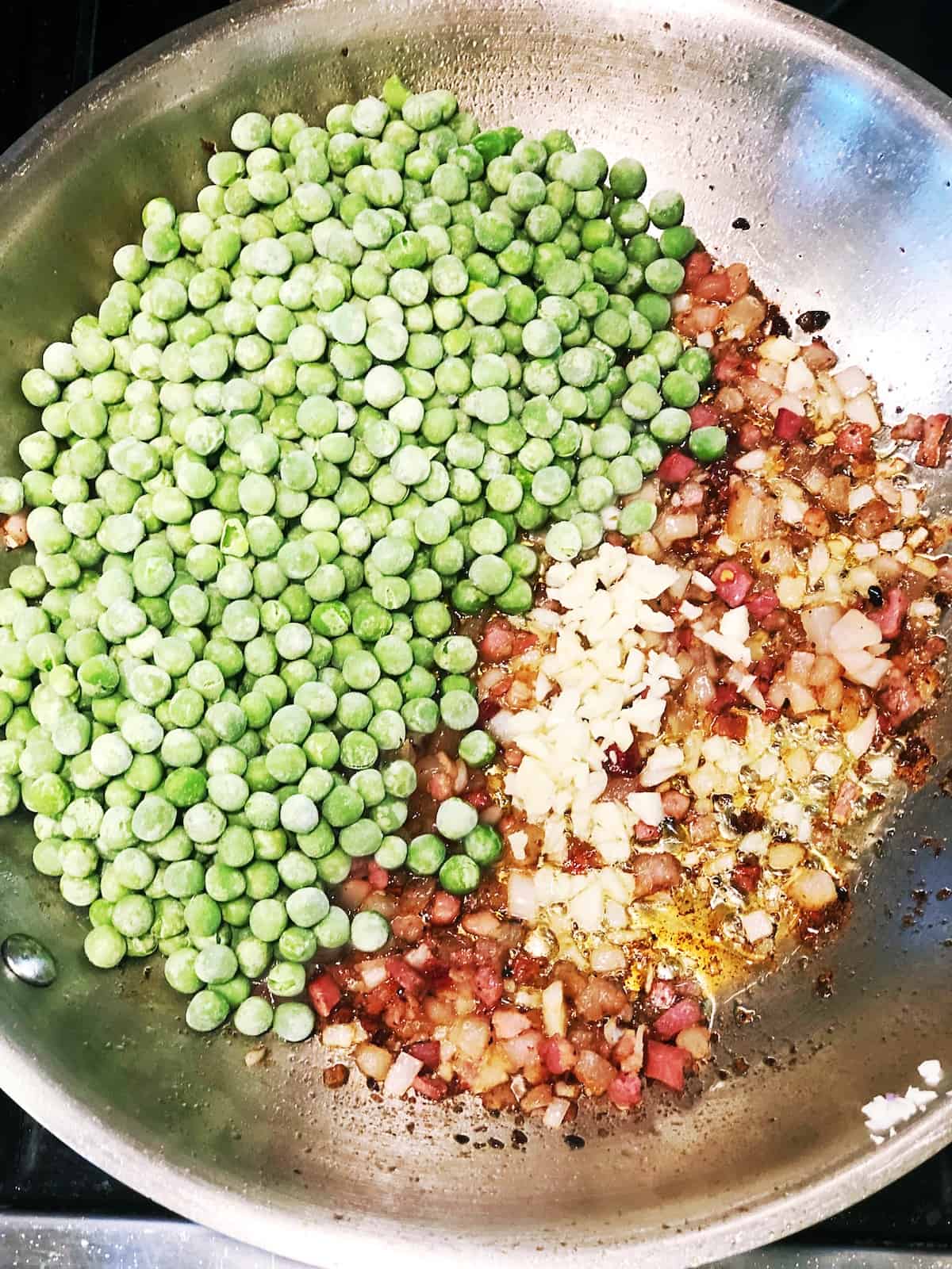 adding peas to pancetta in pan