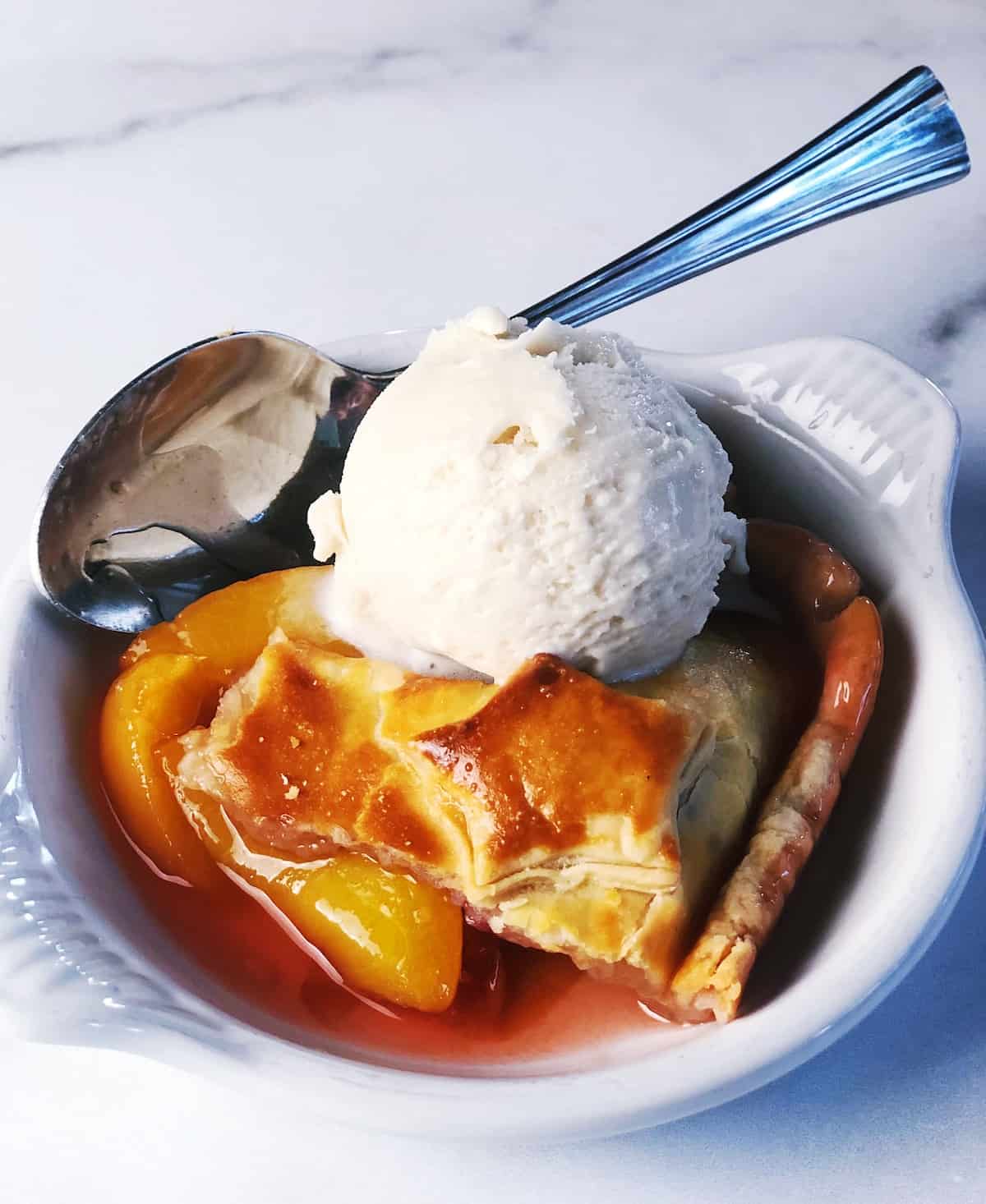 peach cobbler in bowl with ice cream