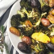 A white dinner plate with roasted potatoes and broccoli