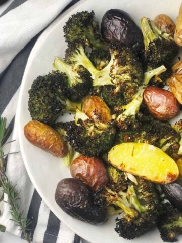 A white dinner plate with roasted potatoes and broccoli