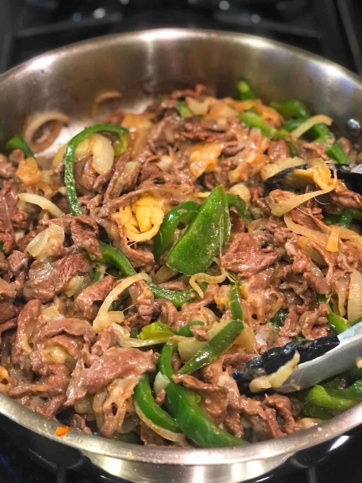 mixing cheese into cheesesteak ingredients