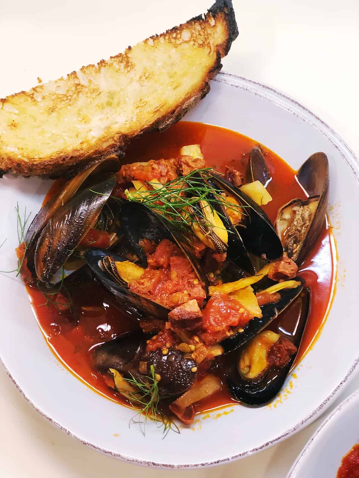 Spanish mussels in bowl with crusty bread on side