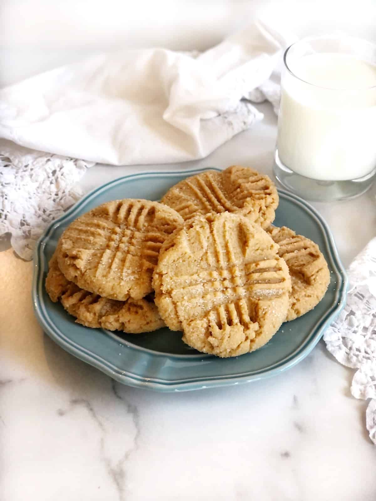 peanut butter cookies on plate with a glass of milk in the background