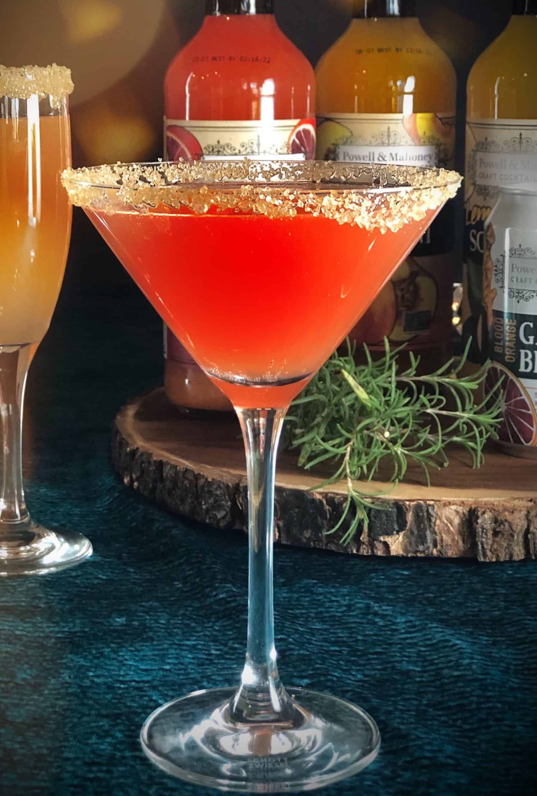 An Aperol martini is sitting on top of a wooden board.