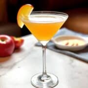 An apple cider martini with a slice of apple on top.