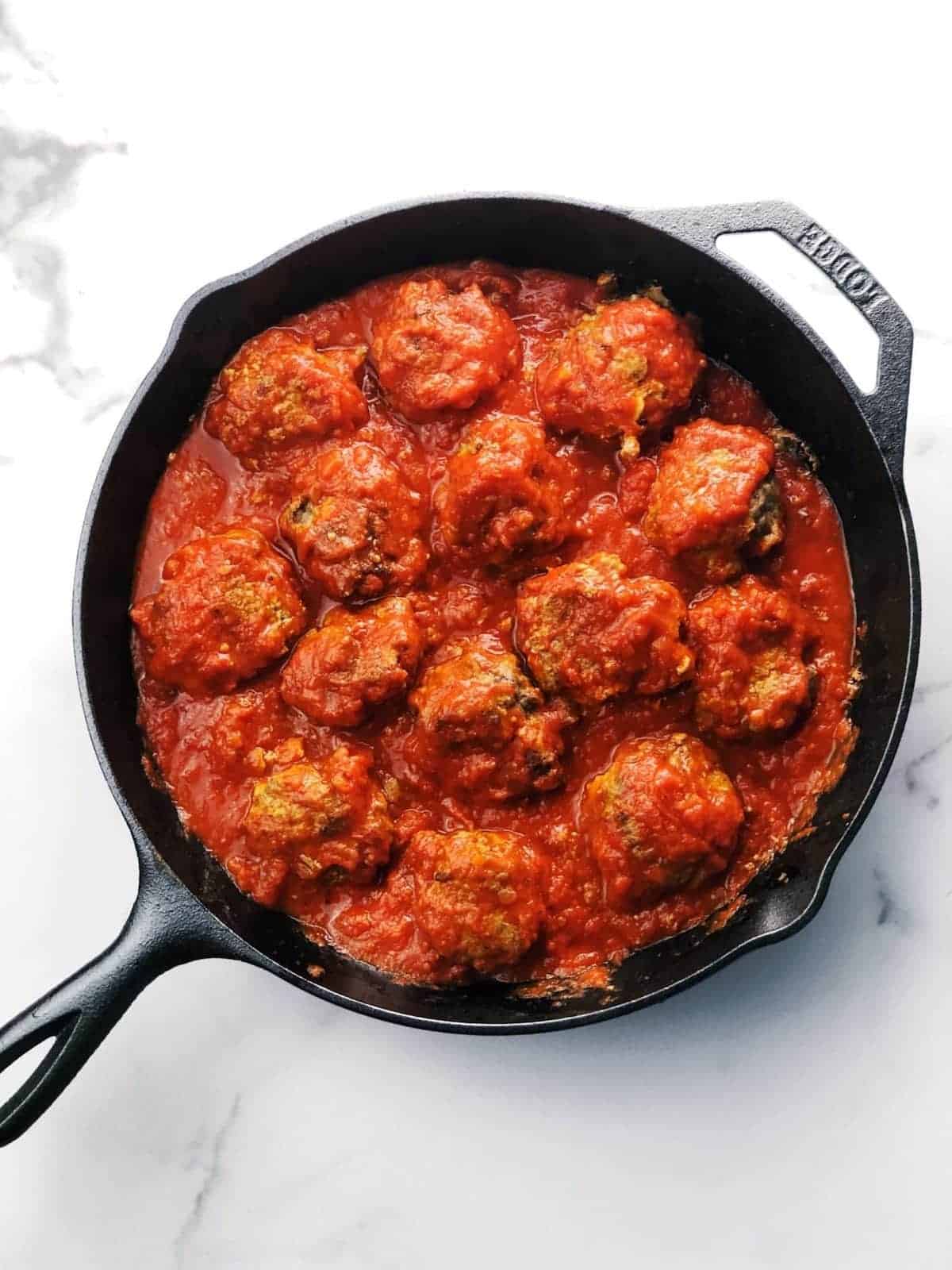 A skillet filled with meatballs and sauce.