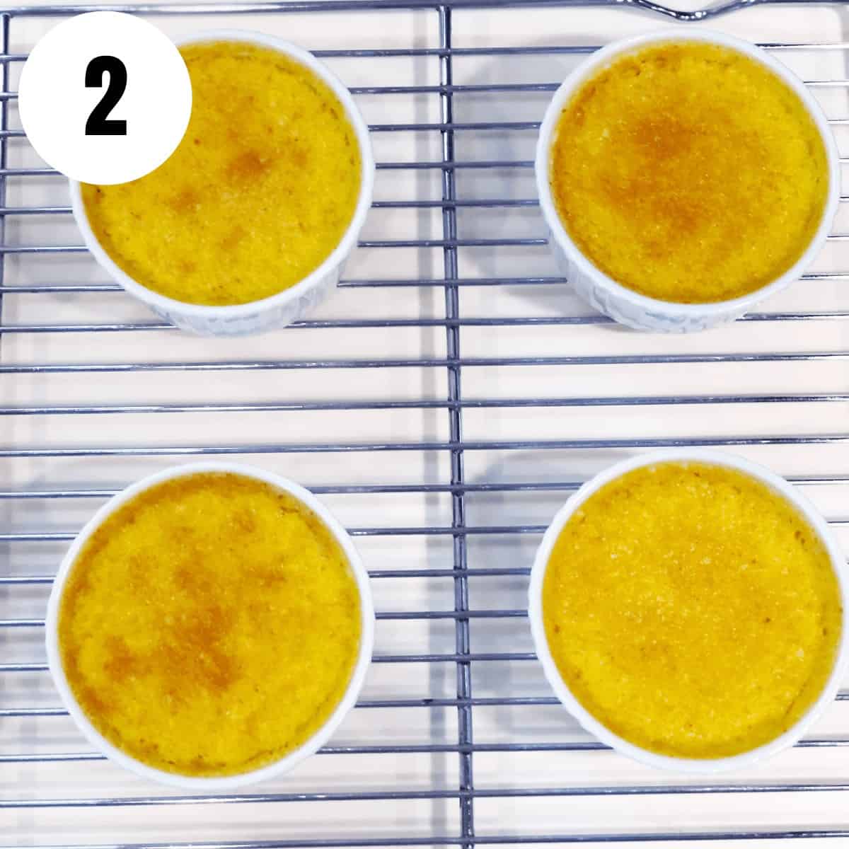 Four bowls of creme brulee sitting on a cooling rack.