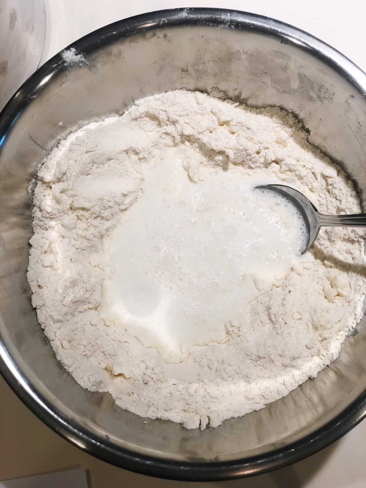 A bowl of flour with a spoon in it.