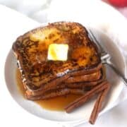 A plate of apple cider french toast with butter and cinnamon.