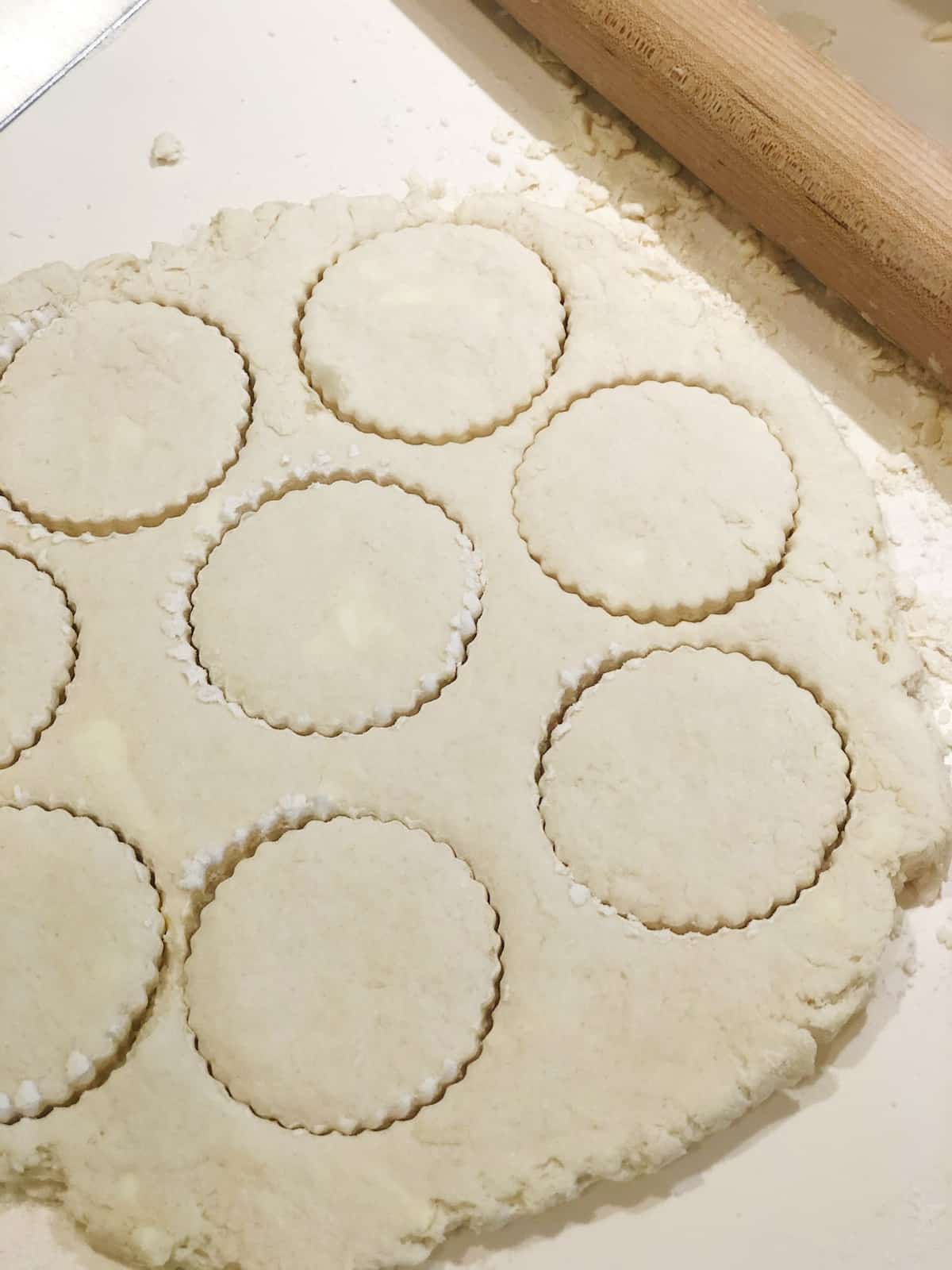 A sheet of dough on a table with a rolling pin.