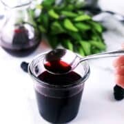 A person pouring blackberry syrup into a bowl.
