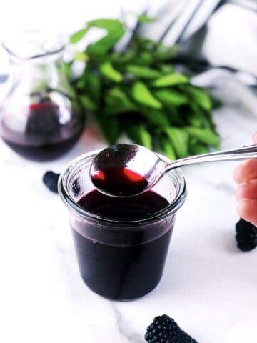A person pouring blackberry syrup into a bowl.