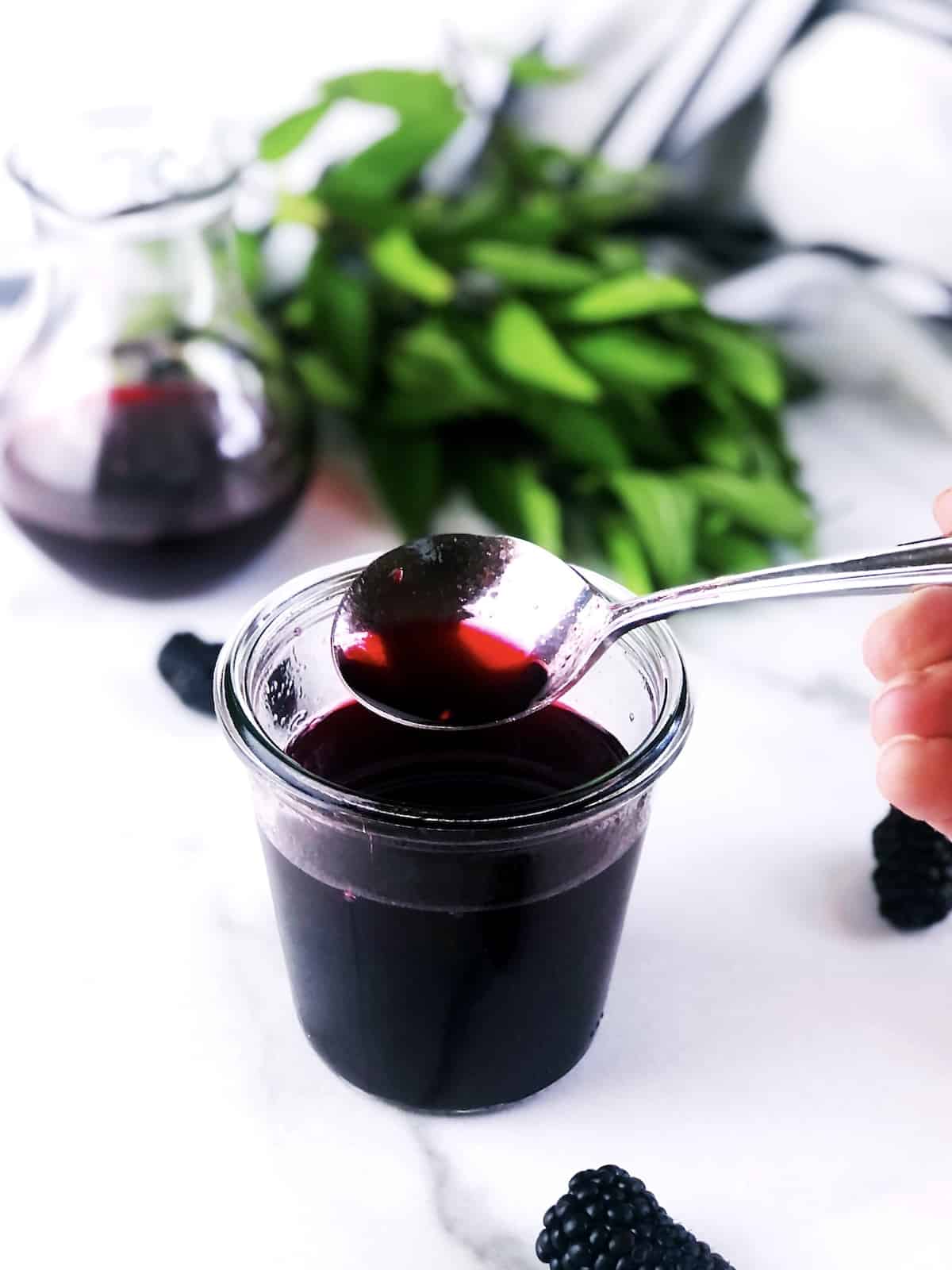 A person pouring blackberry syrup into a bowl.