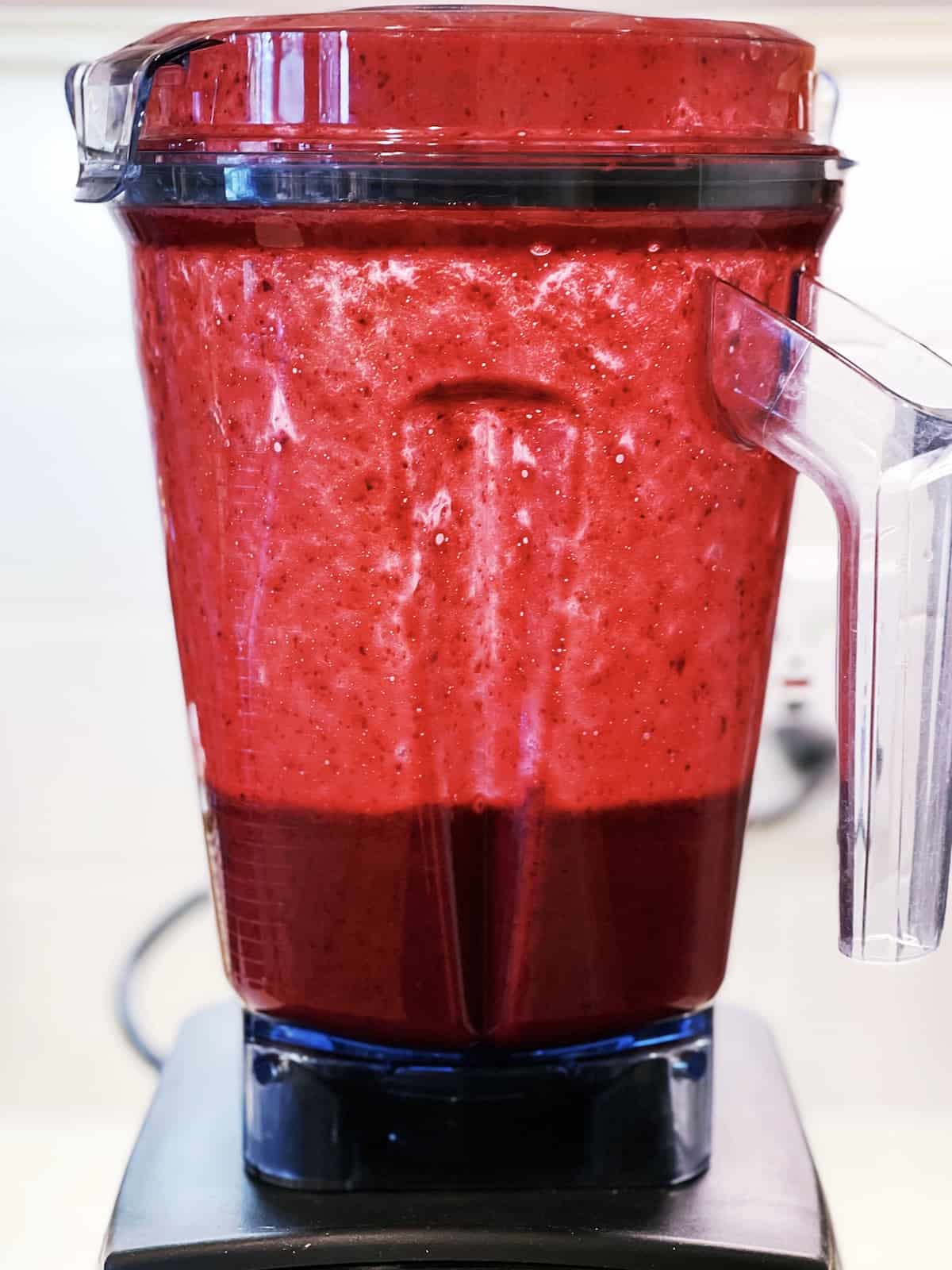 A blender filled with red cherries.