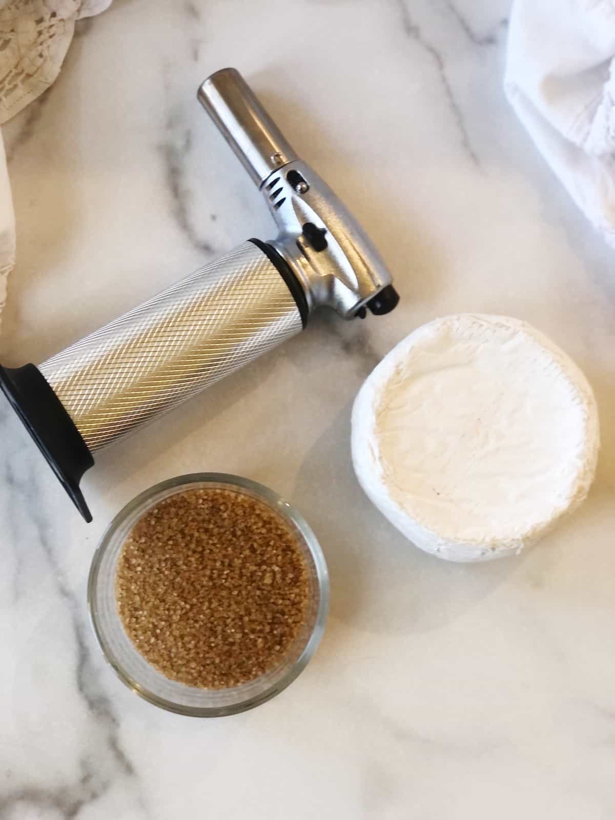A brie cheese and other ingredients on a marble table.