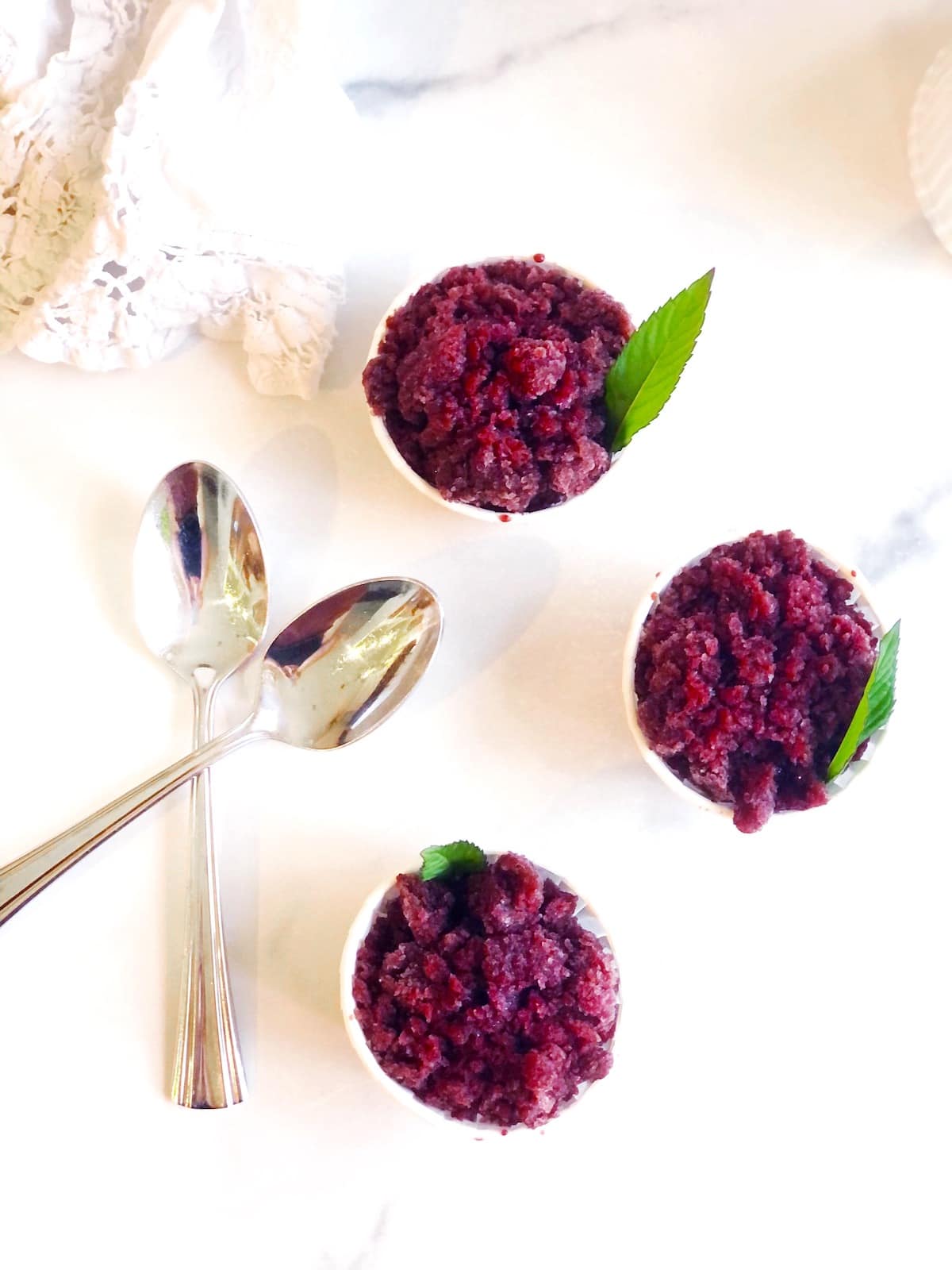 Three small bowls of cherry granita with spoons.