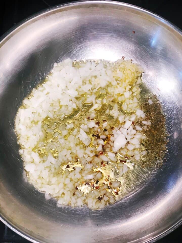 A wok with onions and garlic in it.