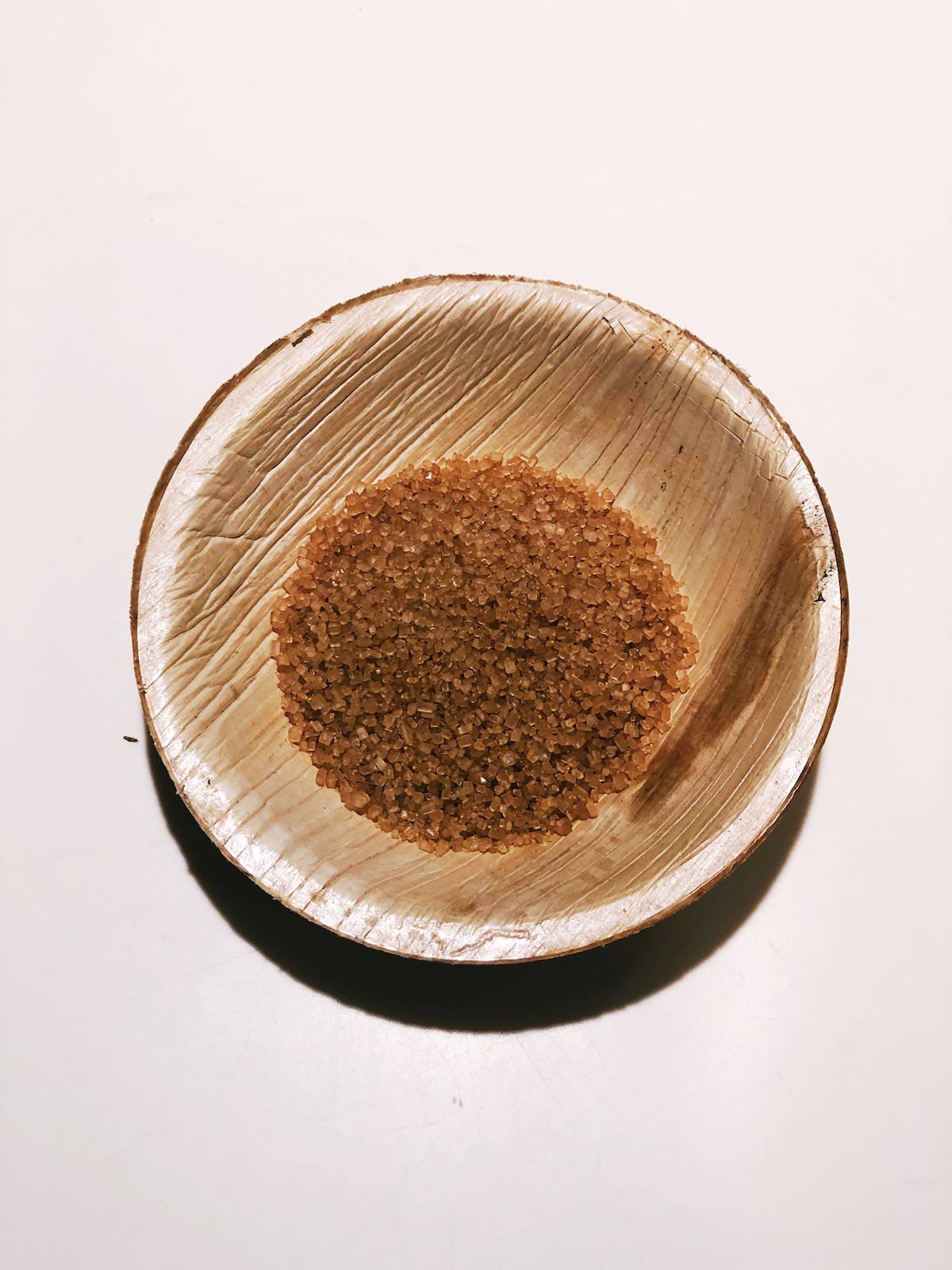 A bowl of brown sugar sitting on a table.