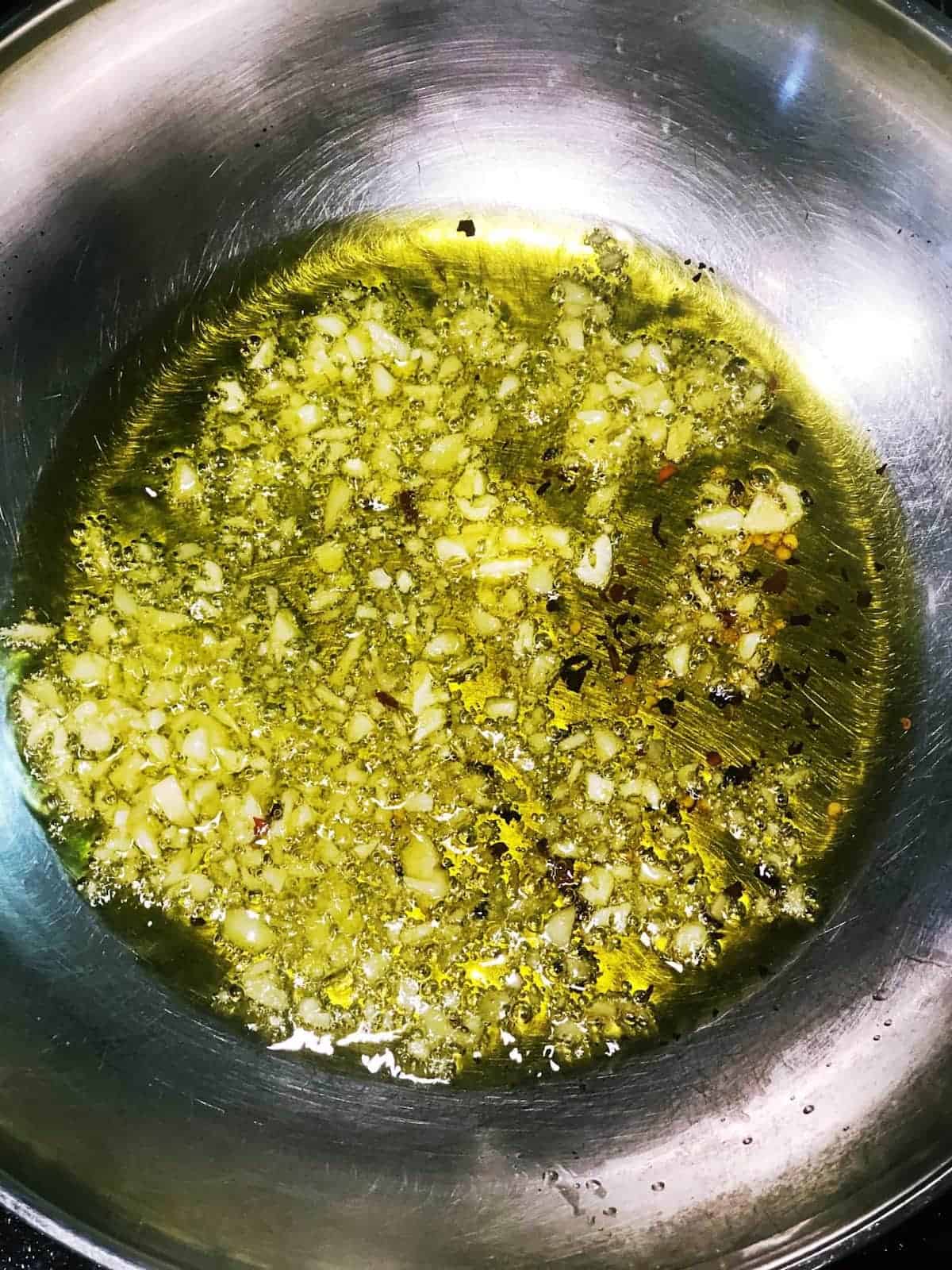 Oil and garlic in a stainless steel pan.