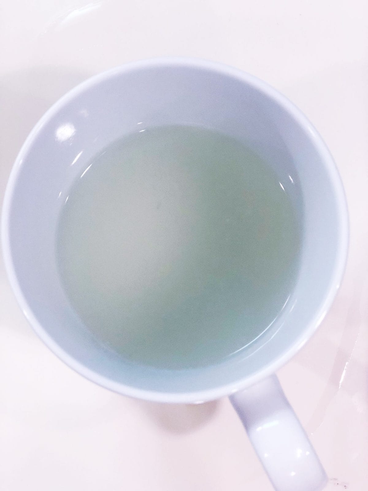 A cup of pasta water sitting on a table.