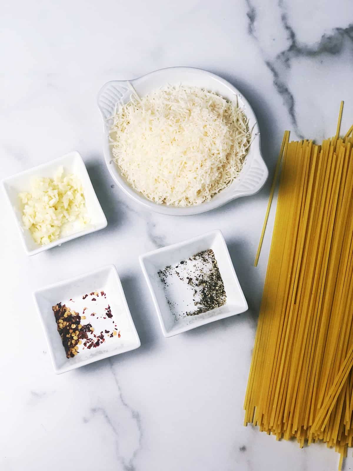 Ingredients for spaghetti with garlic on a marble table.