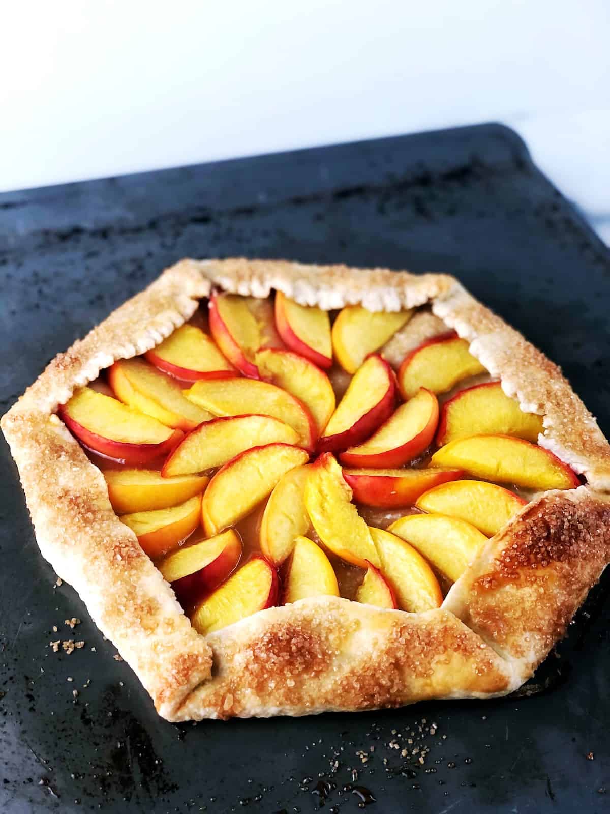 A peach galette on a baking sheet.