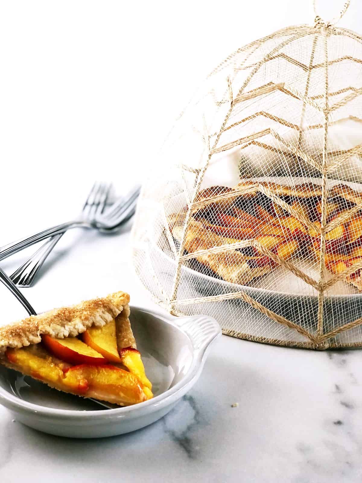 A slice of peach galette on a plate next to a fork.