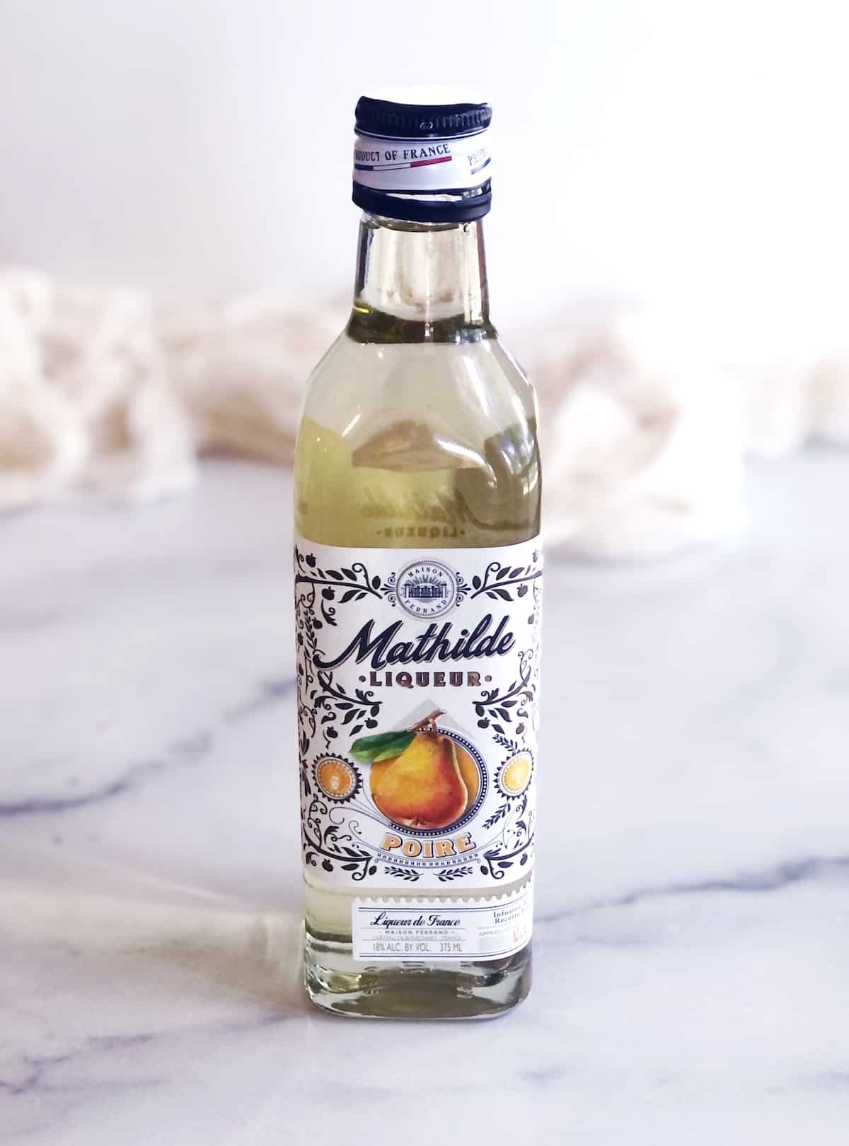 A bottle of pear liqueur on a marble table.