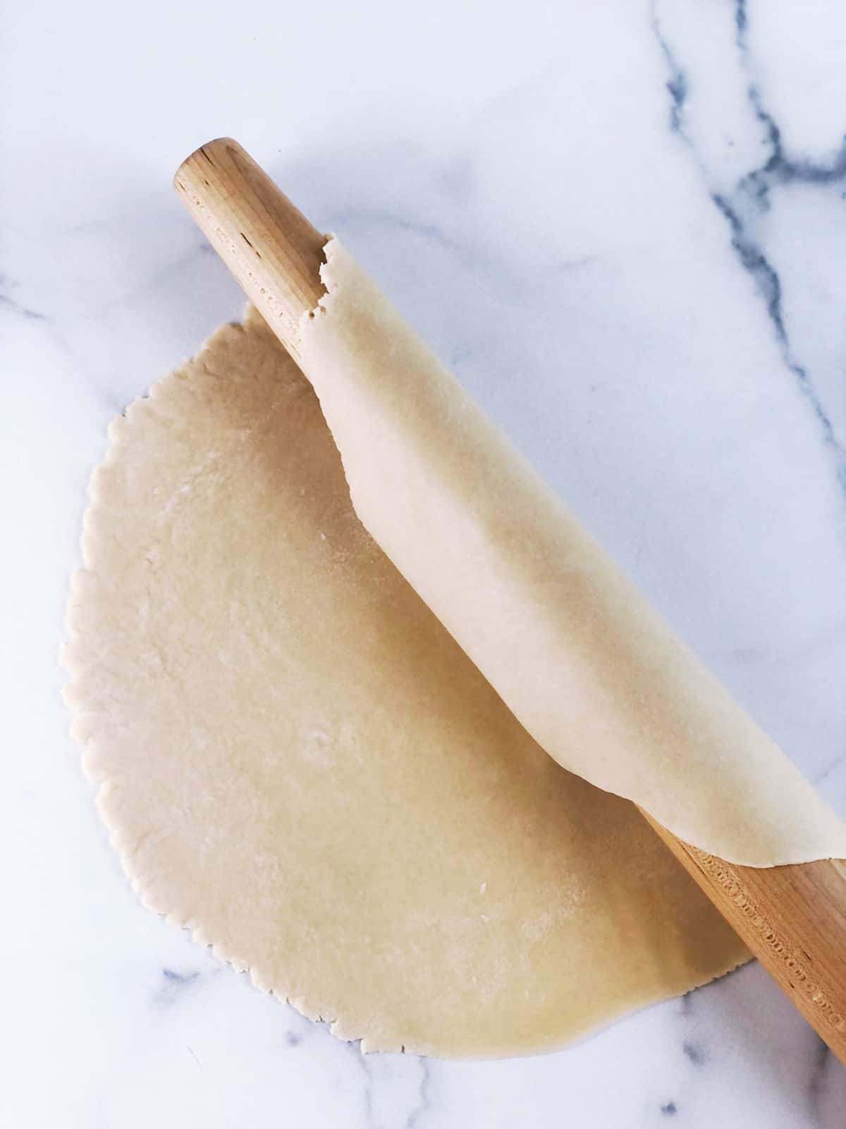 A wooden rolling pin on a marble countertop.