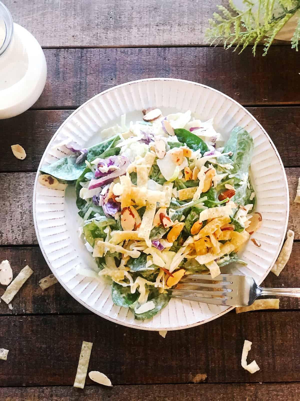 A plate with a salad on a wood table.
