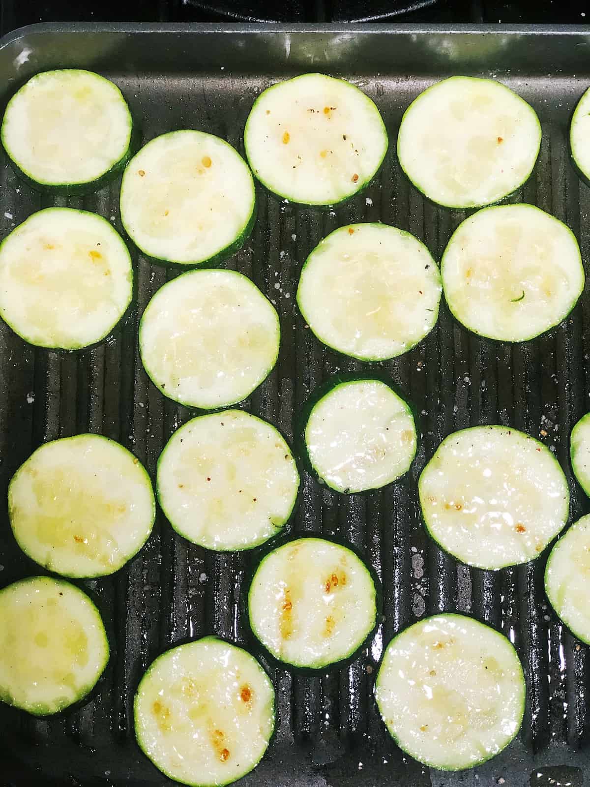 Grilled zucchini slices on a grill.