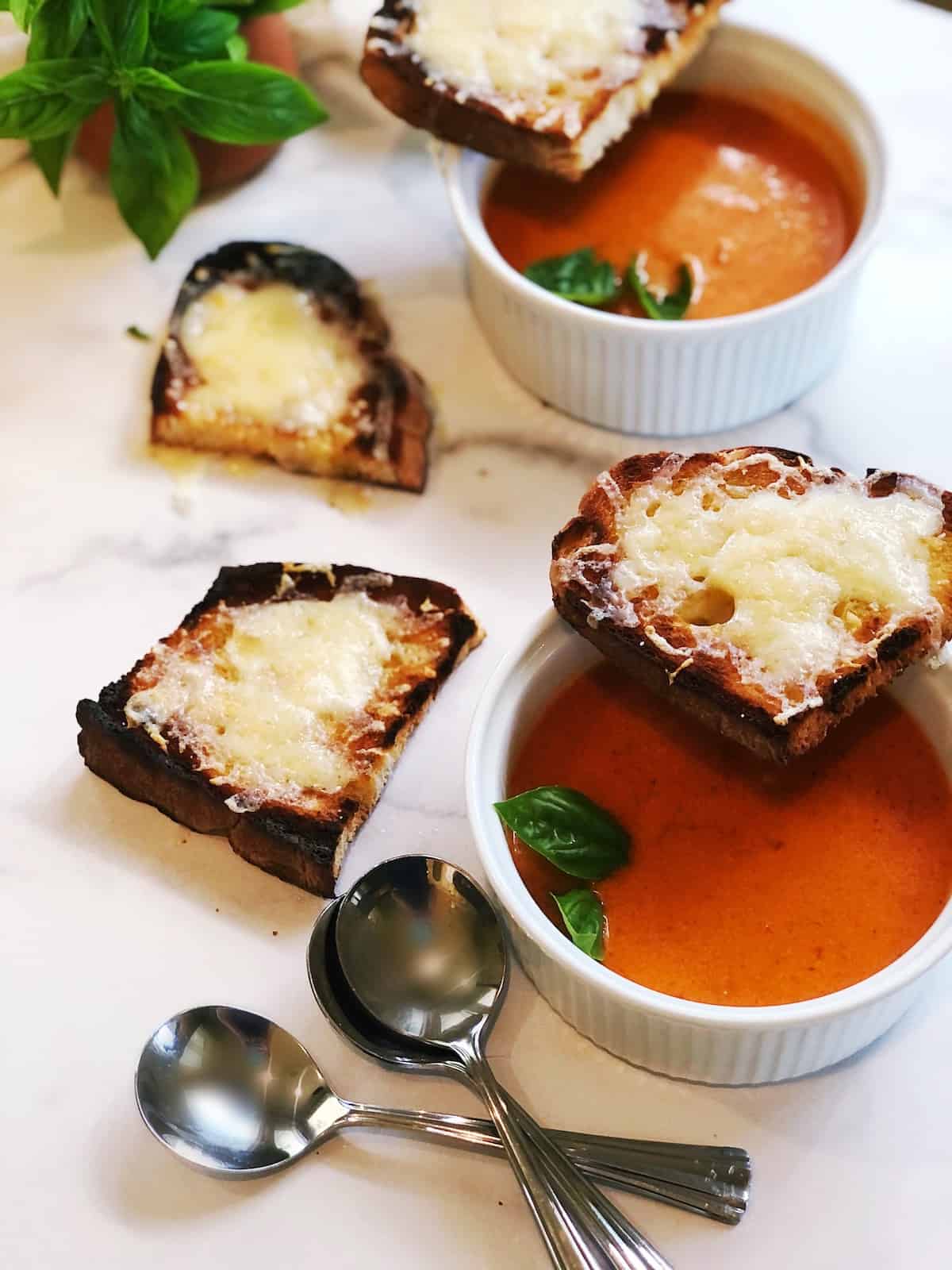 A bowl of tomato soup with a slice of bread.