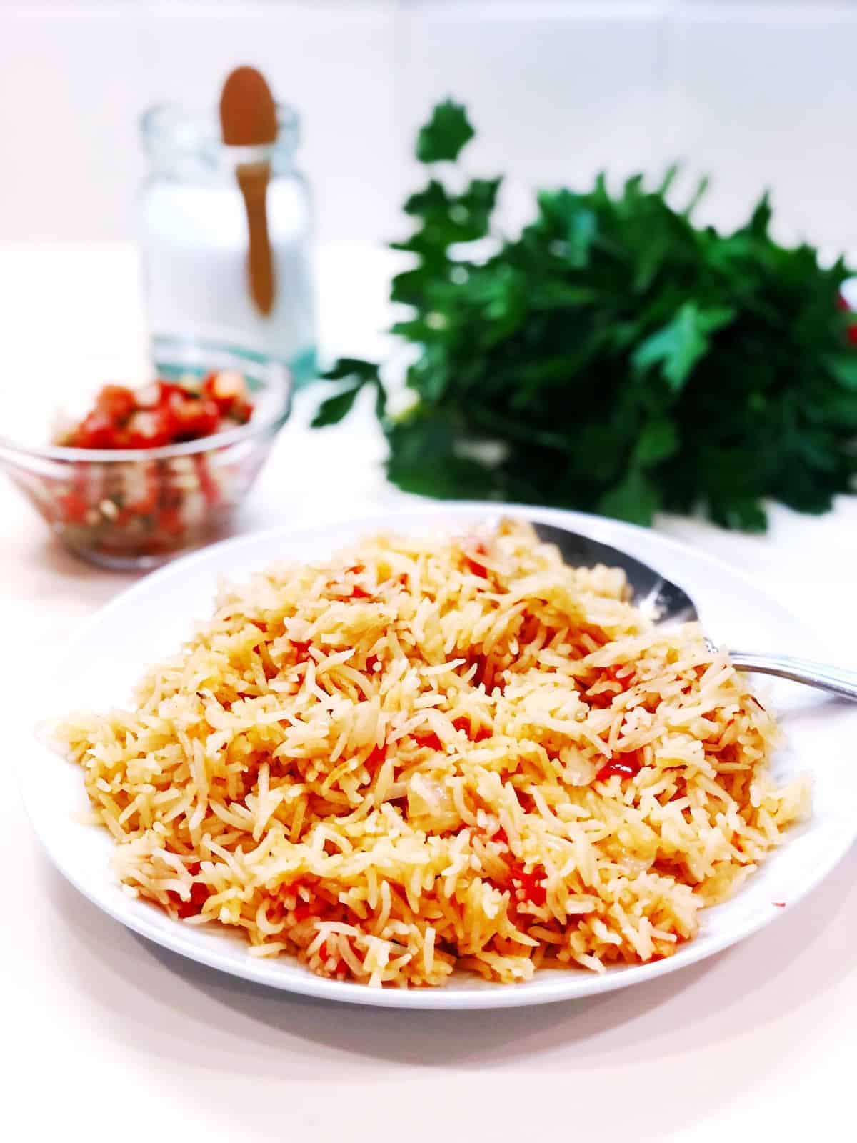 A plate of Mexican rice and vegetables on a white table.
